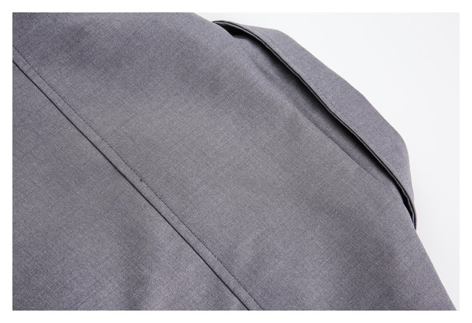 Close-up of gray garment fabric showing a curved folded edge and a stitched seam.