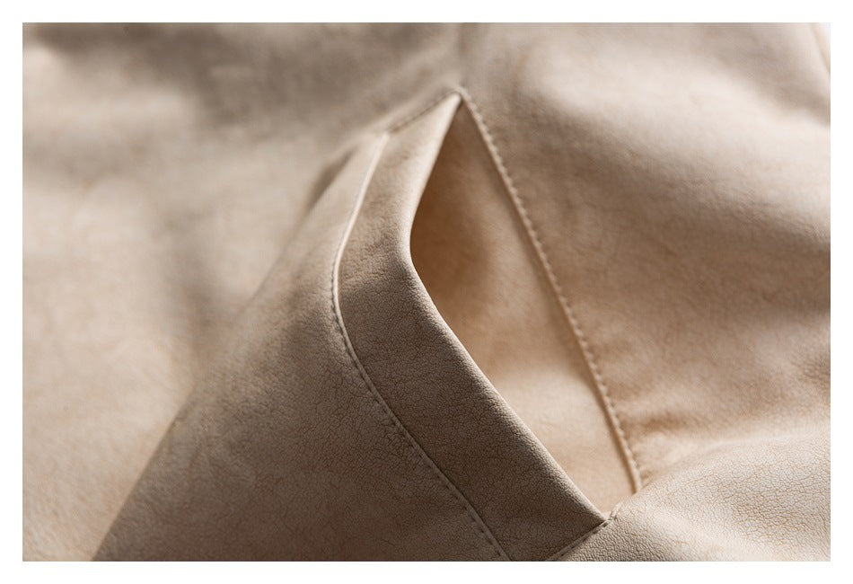 Close-up of a pocket opening on the cream jacket, showing its shape and stitched edge.