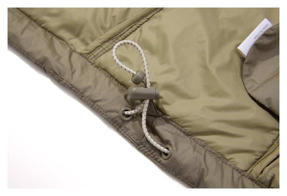 Close-up of a tan jacket hem with an elastic drawcord, toggle, metal eyelets, and a small white label.