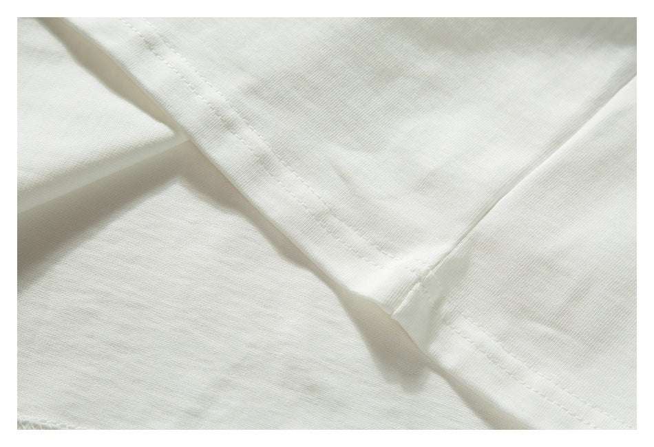 Close-up of intersecting seams and stitching on off-white T-shirt fabric.