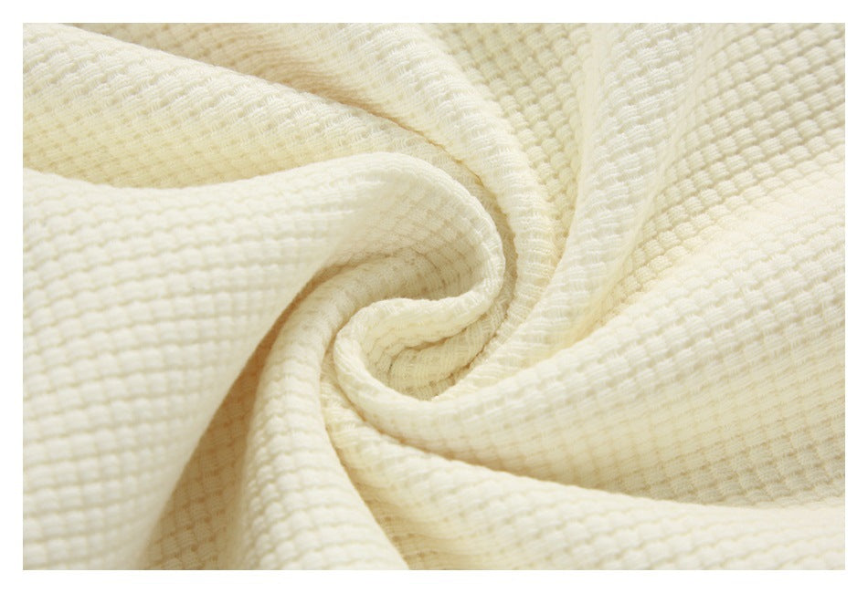 Close-up of off-white textured fabric gathered into soft folds.
