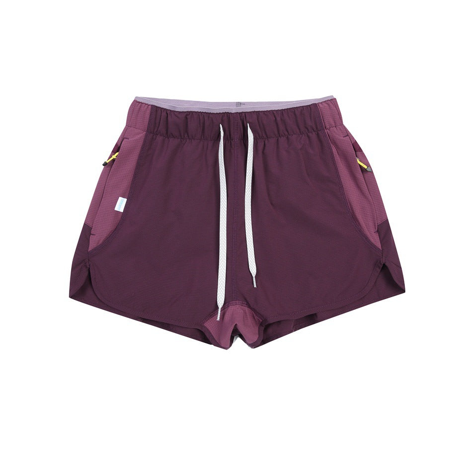 Dark purple shorts with white drawstring, lighter purple side panels and curved split hems, flat lay