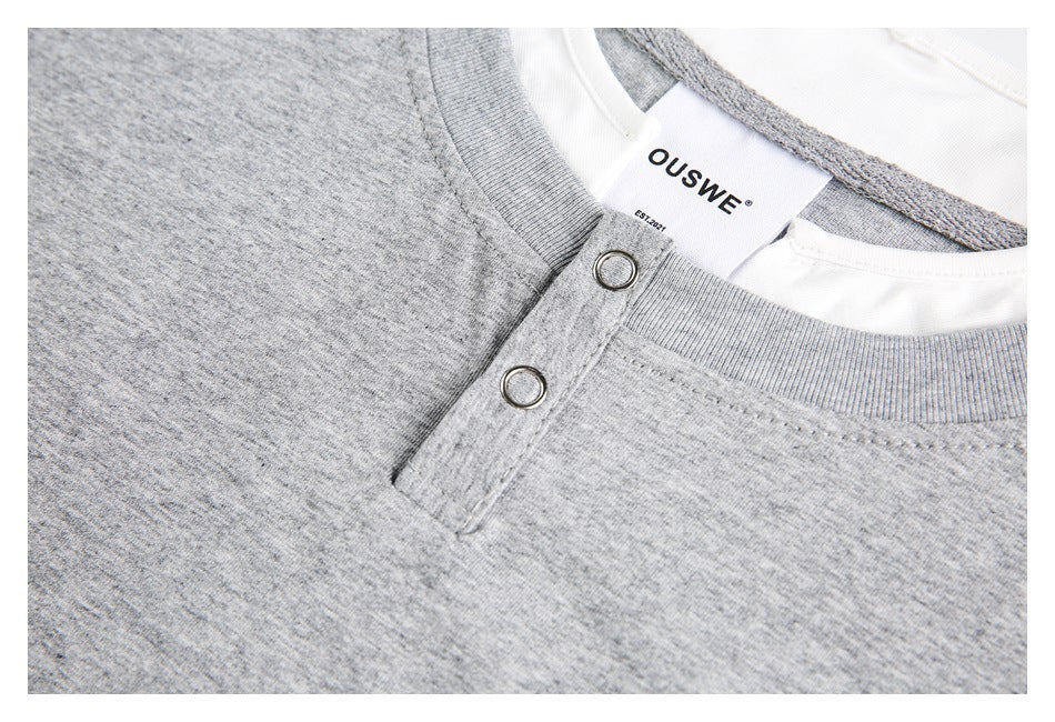 Close-up of a heather gray shirt neckline with two metal snaps and a white brand label.