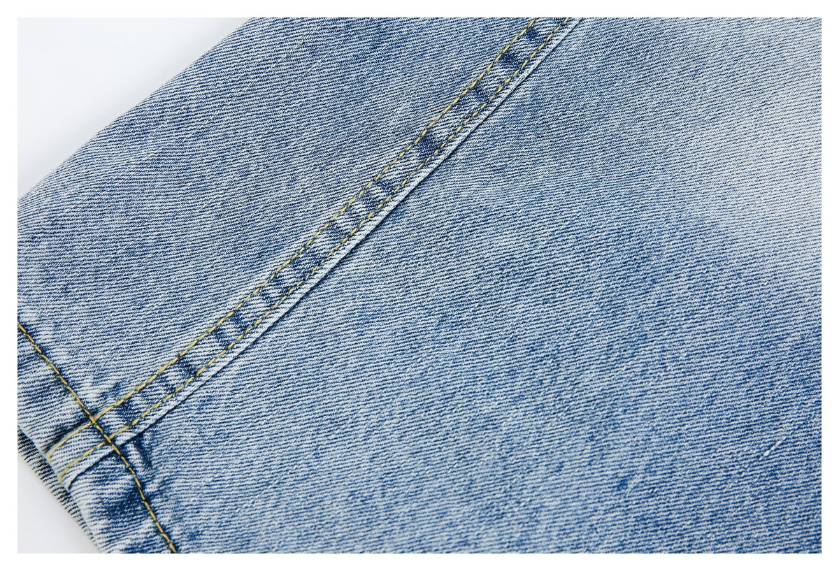 Close-up of light blue jeans showing a long double-stitched seam and intersecting stitching.