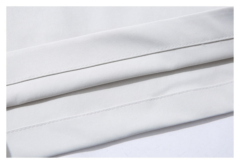 Close-up of parallel stitched edges on folded pale gray trouser fabric.