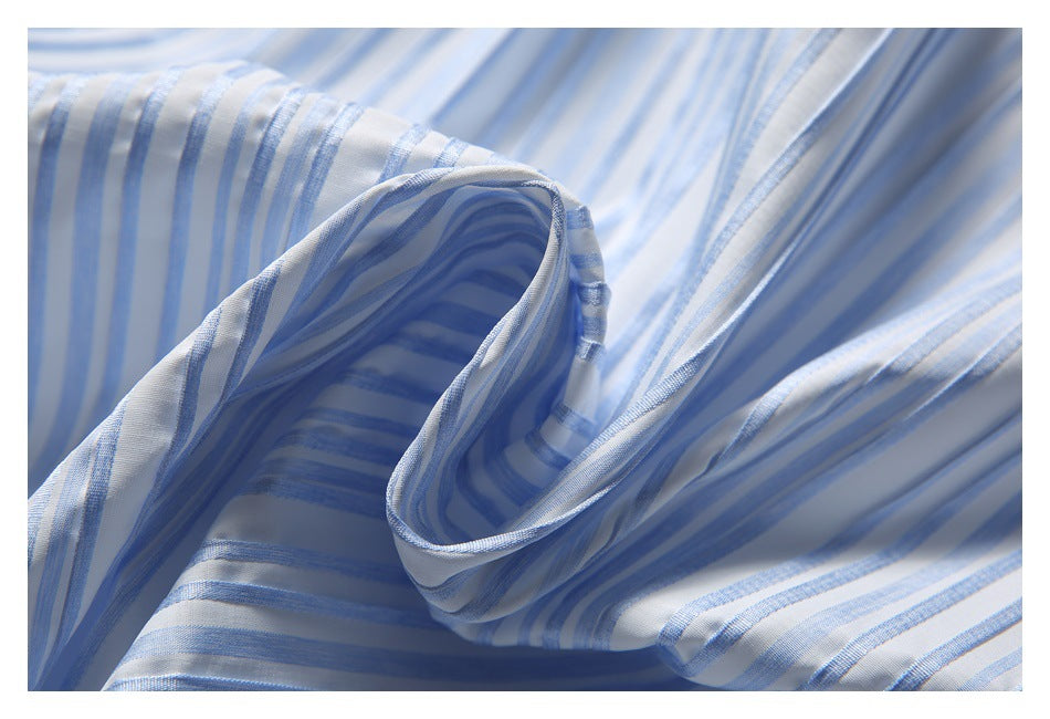 Close-up of a white shirt with blue stripes, showing a folded cuff opening and stitched edges.