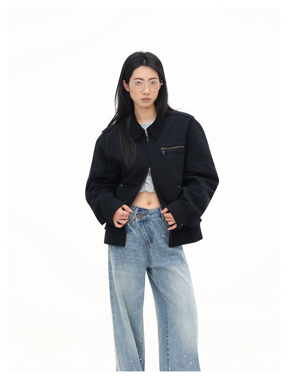 Closer front view of a model wearing an open black collared jacket with a zip chest pocket and light-blue embellished jeans.