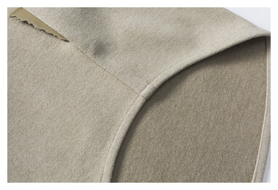 Close-up of a curved pocket opening on beige woven fabric, with a small tan tab near the edge.