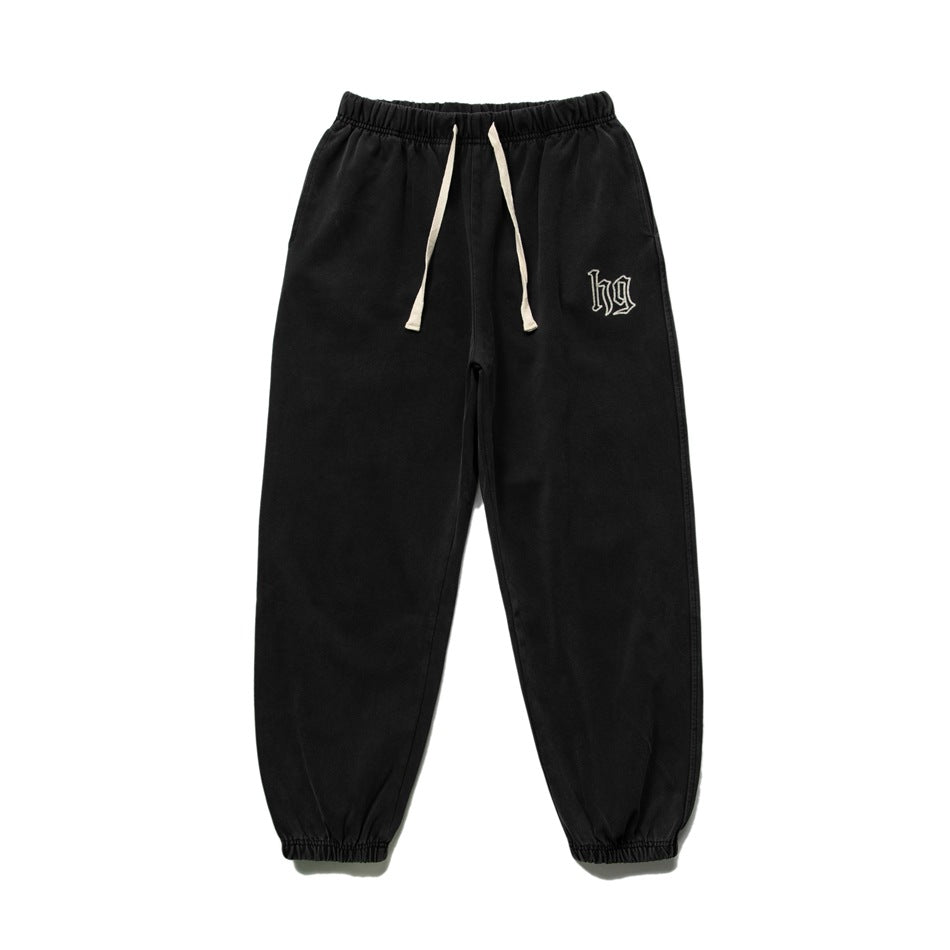 Black sweatpants flat lay with cream drawstring, elastic cuffs and embroidered hg logo