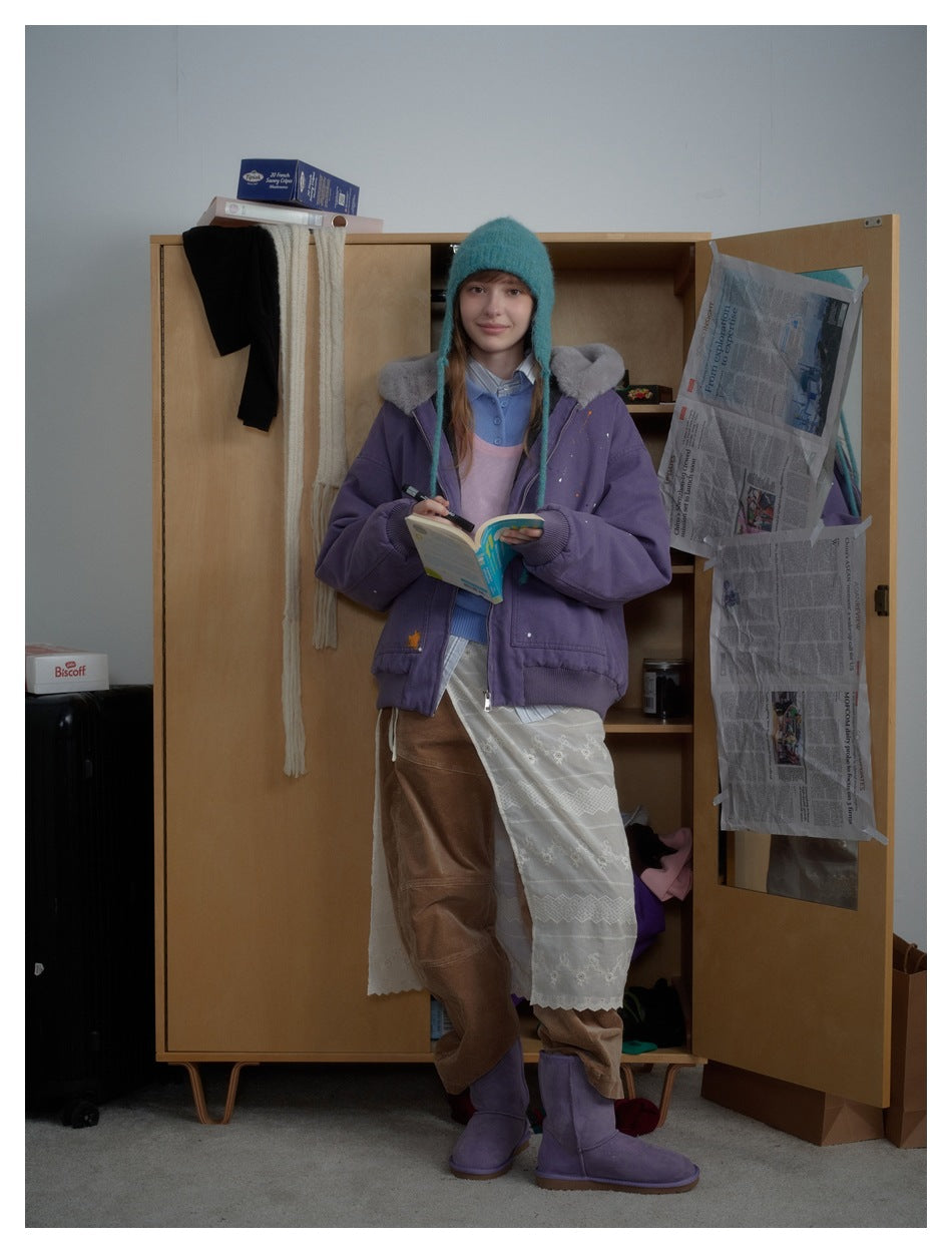 Model wearing a purple oversized jacket with a gray plush collar, shown nearly full length.