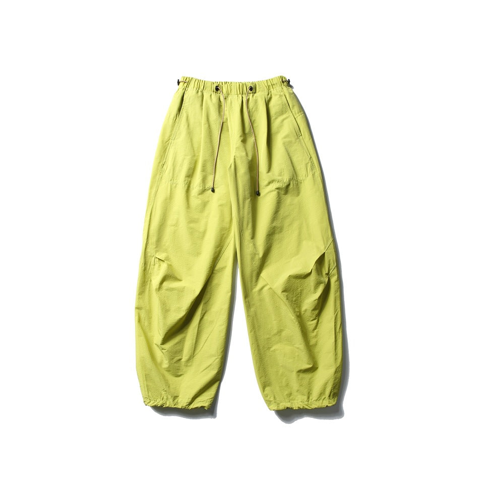 Neon yellow-green wide-leg parachute pants with drawcord waistband, flat lay front view