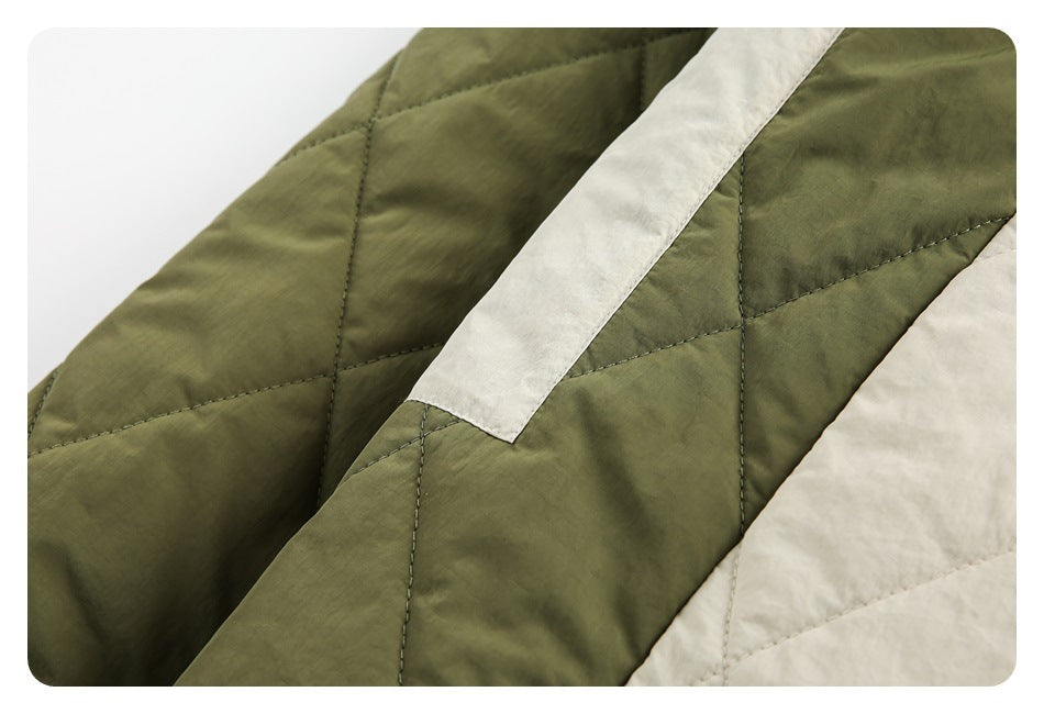 Close-up of olive quilted fabric with cream contrasting panels and visible stitching.