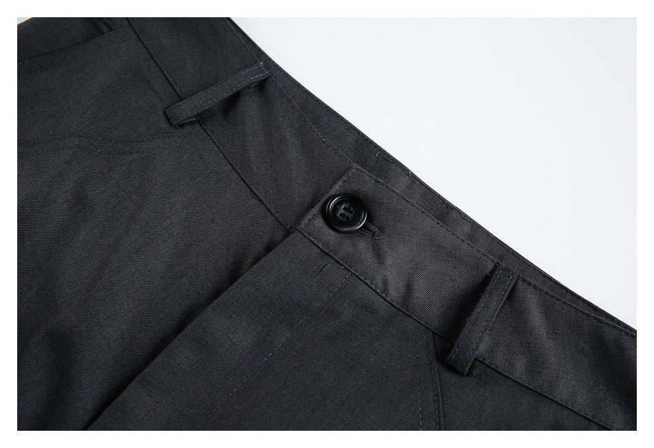 Close-up of charcoal trousers showing the waistband, black button, belt loops, and stitching.