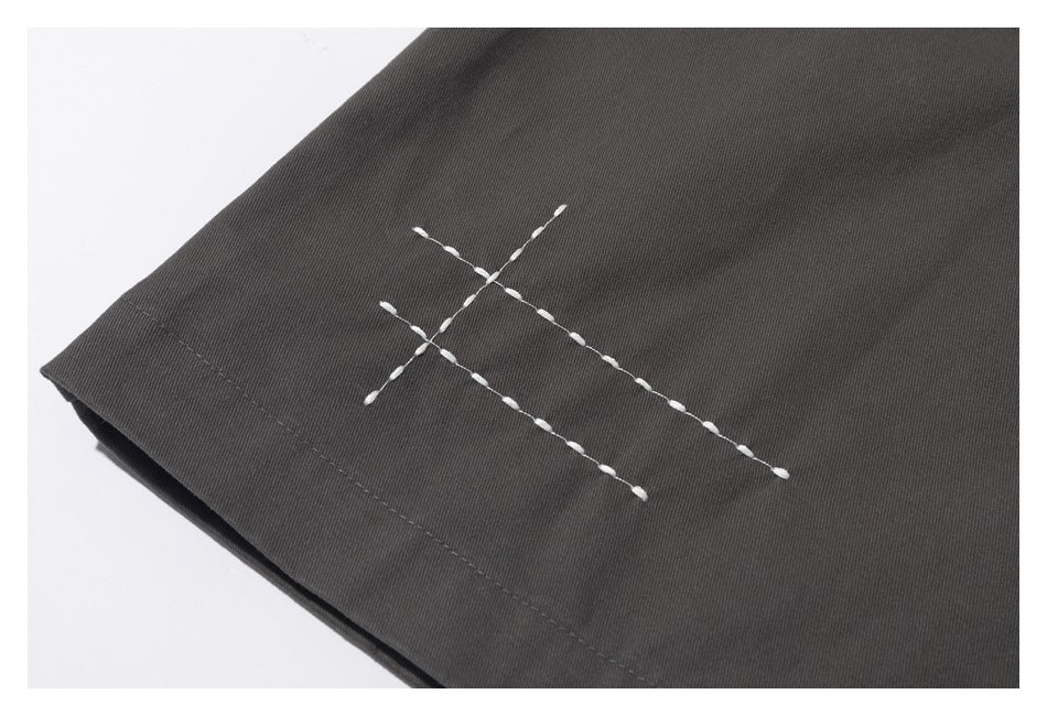 Close-up of white crossed decorative stitching on a dark charcoal garment.