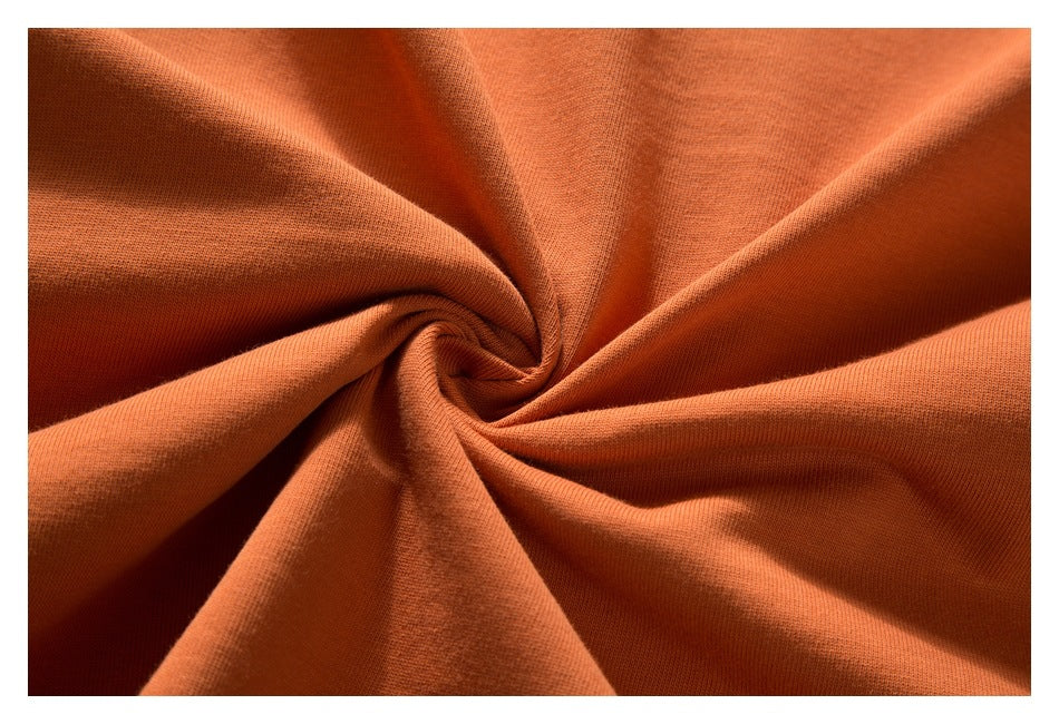 Close-up of orange fabric gathered into folds, showing its surface texture.