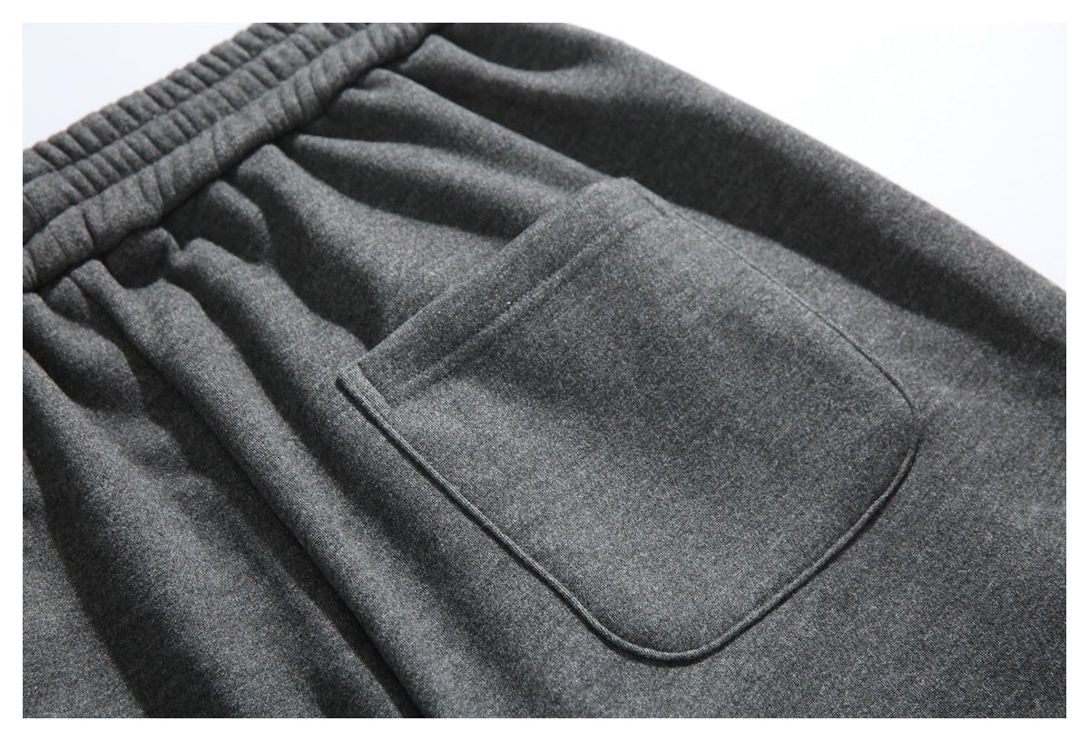 Close-up of the large rounded patch pocket and gathered waist on charcoal gray pants.