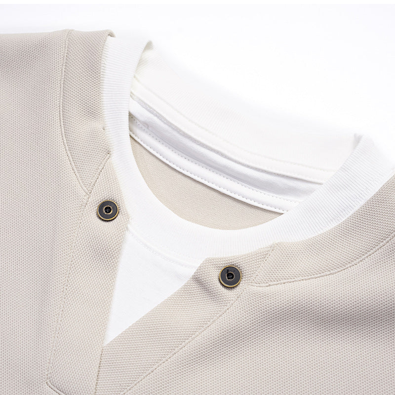 Close-up of a light beige shirt's layered white collar, split placket, and two dark buttons.