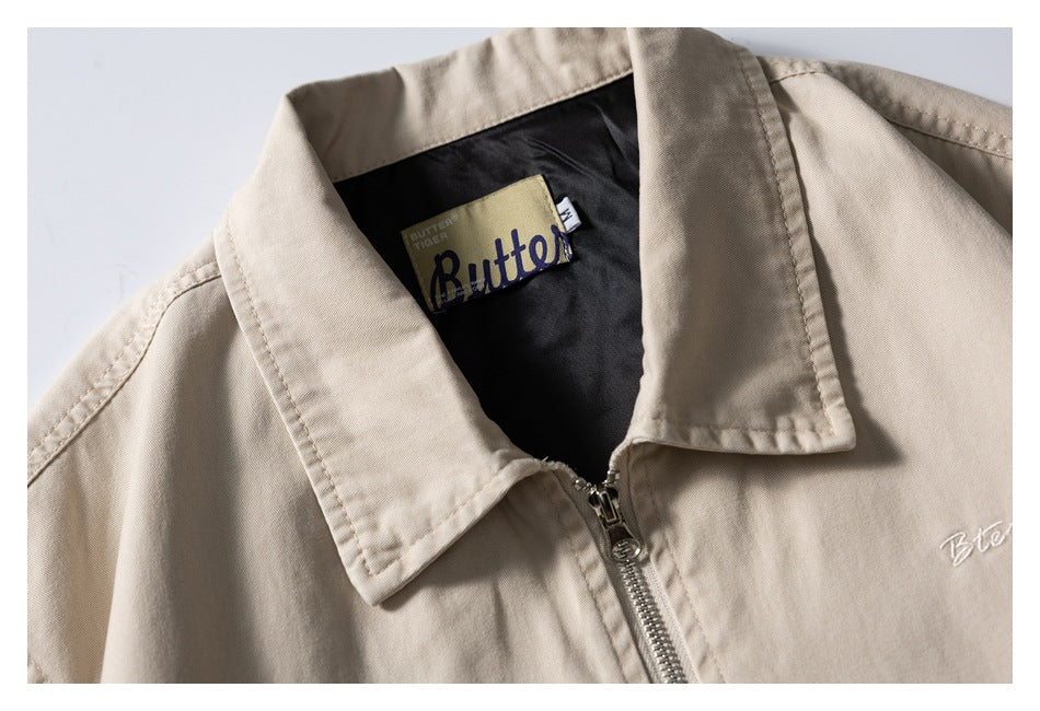 Close-up of a beige jacket collar, zipper, black lining, and sewn-in label.