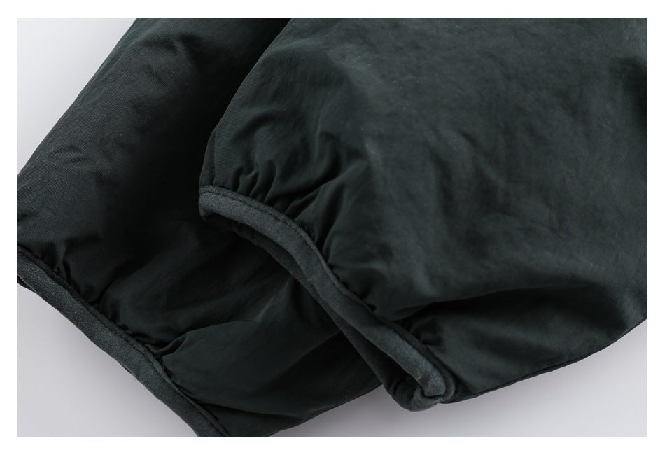Close-up of a dark jacket sleeve with a gathered, dark-trimmed cuff.