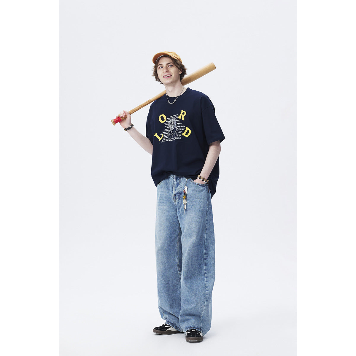 Model wearing a navy oversized graphic T-shirt with yellow lettering and loose blue jeans.