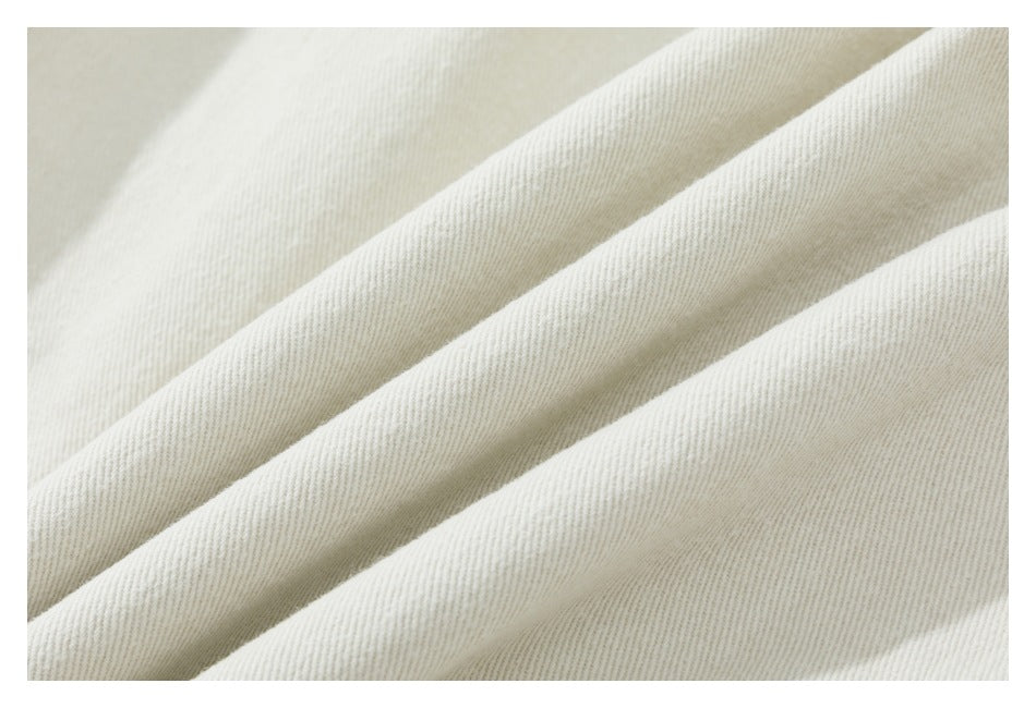 Macro view of the light beige trouser fabric, showing its fine diagonal weave.