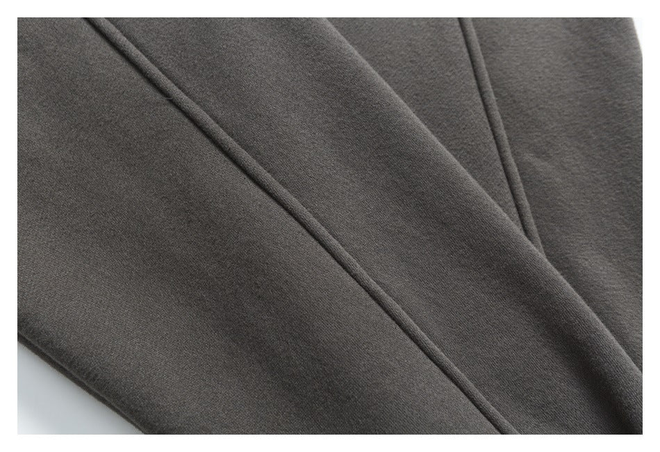 Close-up of a dark charcoal garment panel with diagonal seams and narrow piping.