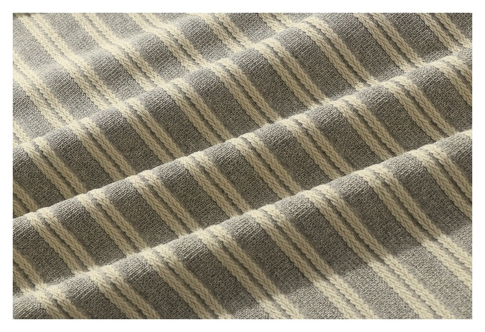 Close-up of gray-beige knit fabric with raised cream stripes and a textured weave.