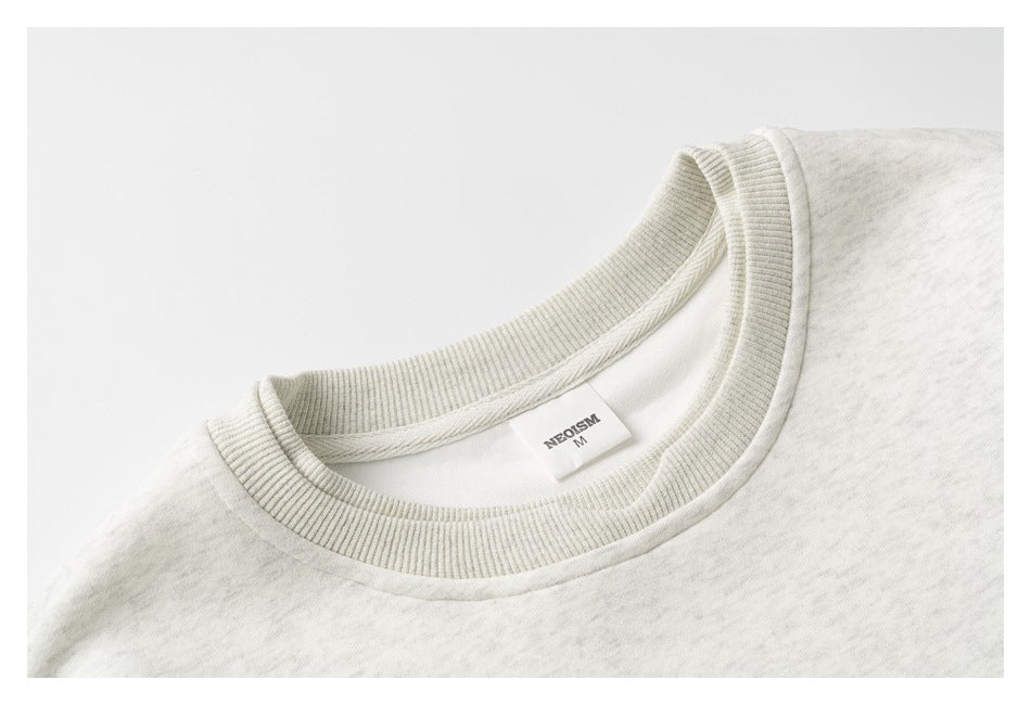 Close-up of the light heather gray sweatshirt's ribbed crew neckline and inside label.