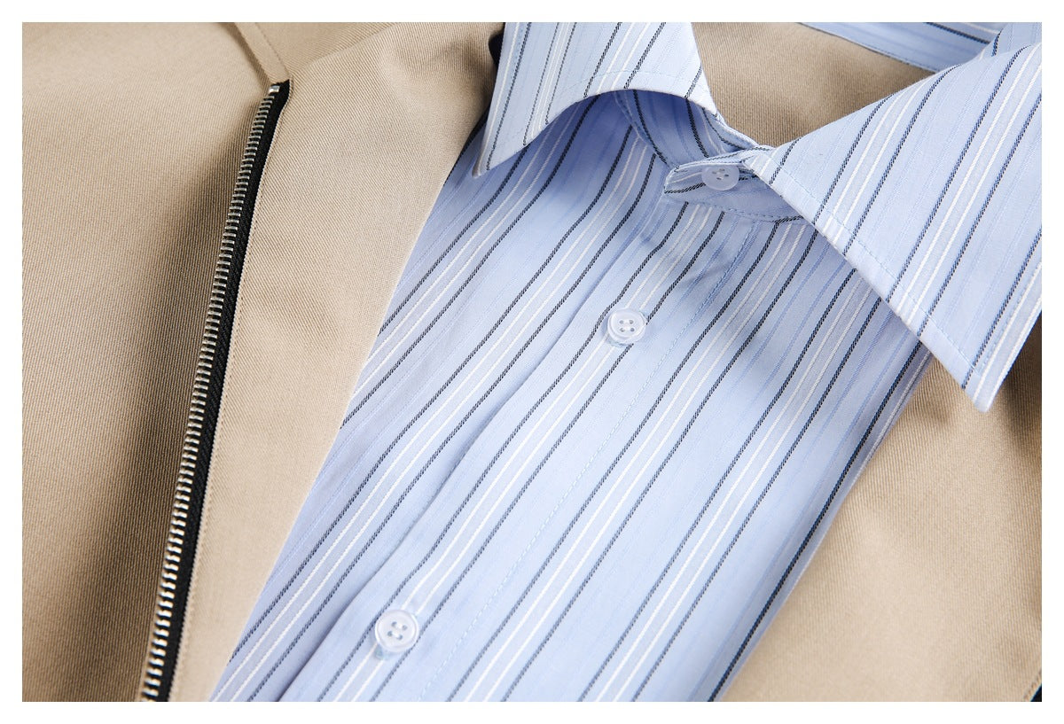Close-up of a light blue striped button-up shirt beneath an open beige jacket with a zipper.