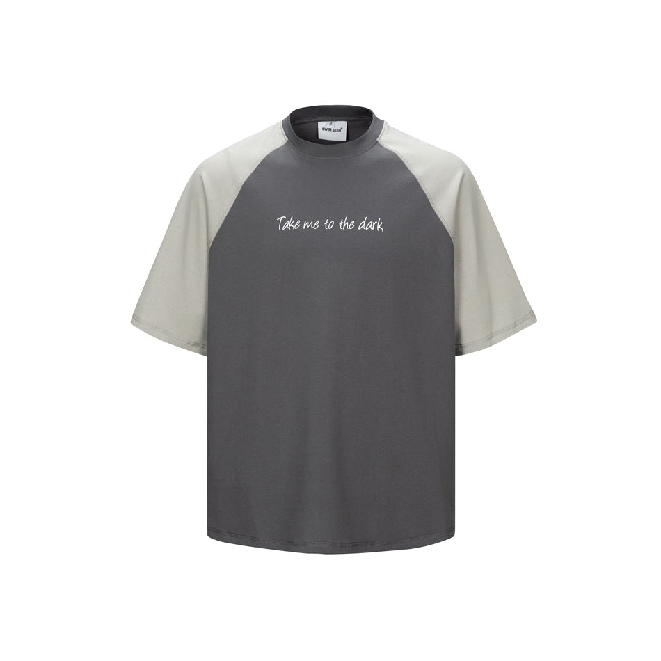 Dark gray crew-neck T-shirt with light gray raglan sleeves and small white script print on the chest, front view