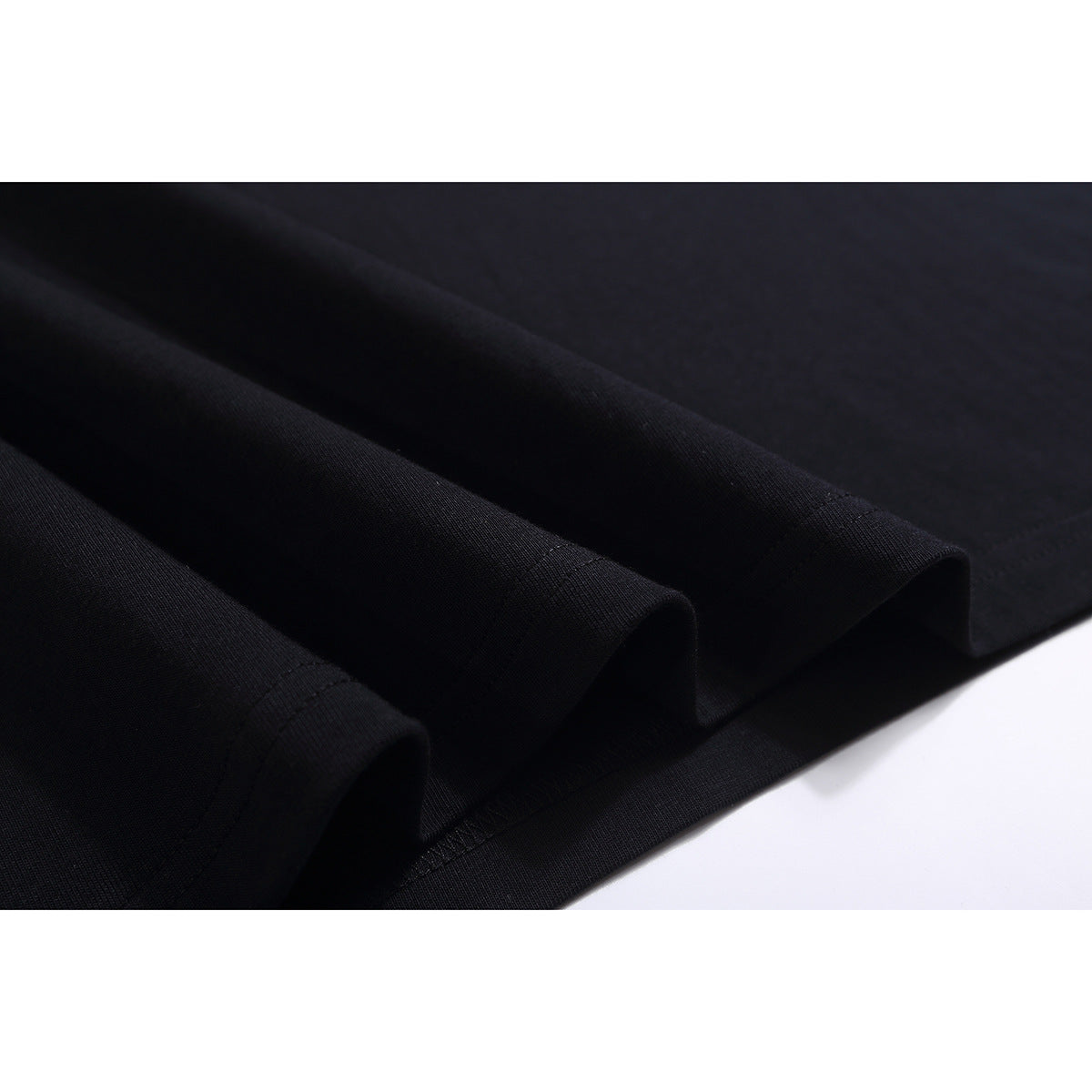 Close-up of the folded hem and stitching on a black T-shirt.