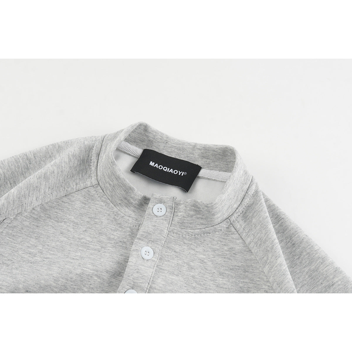 Close-up of a heather gray shirt's band collar, white-button placket, and neck label.