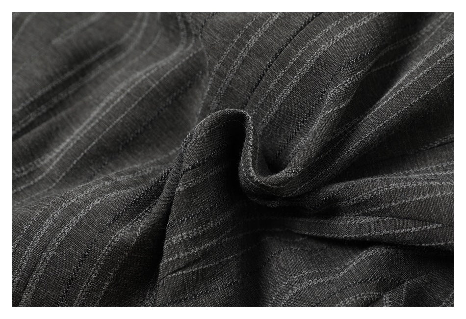 Close-up of charcoal striped fabric gathered into folds, showing its texture and drape.