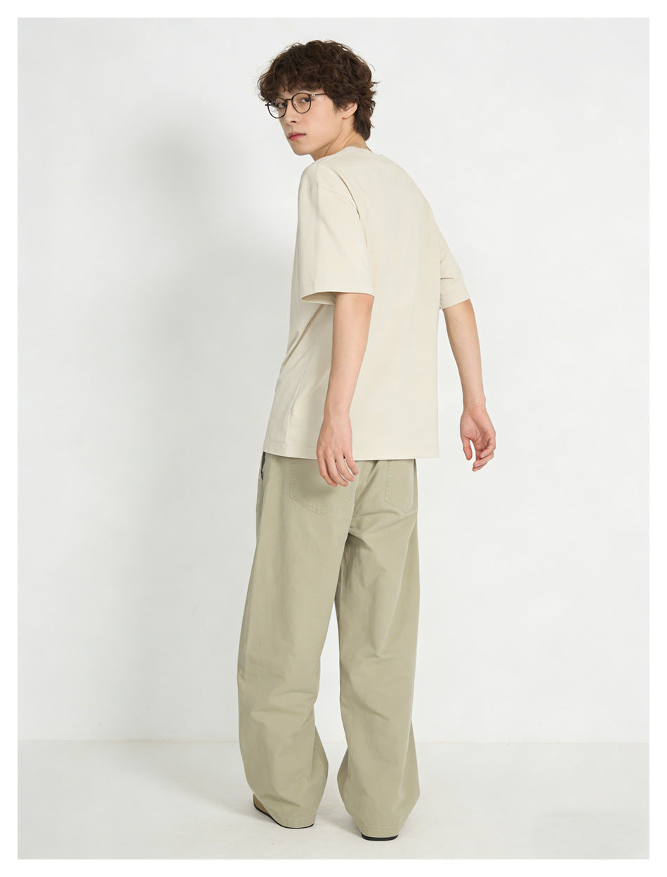 Model looking back in an off-white short-sleeve T-shirt and loose light khaki trousers, seen from behind.