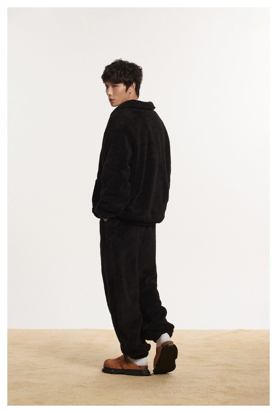 Rear view of a model wearing a black plush pullover and matching pants.