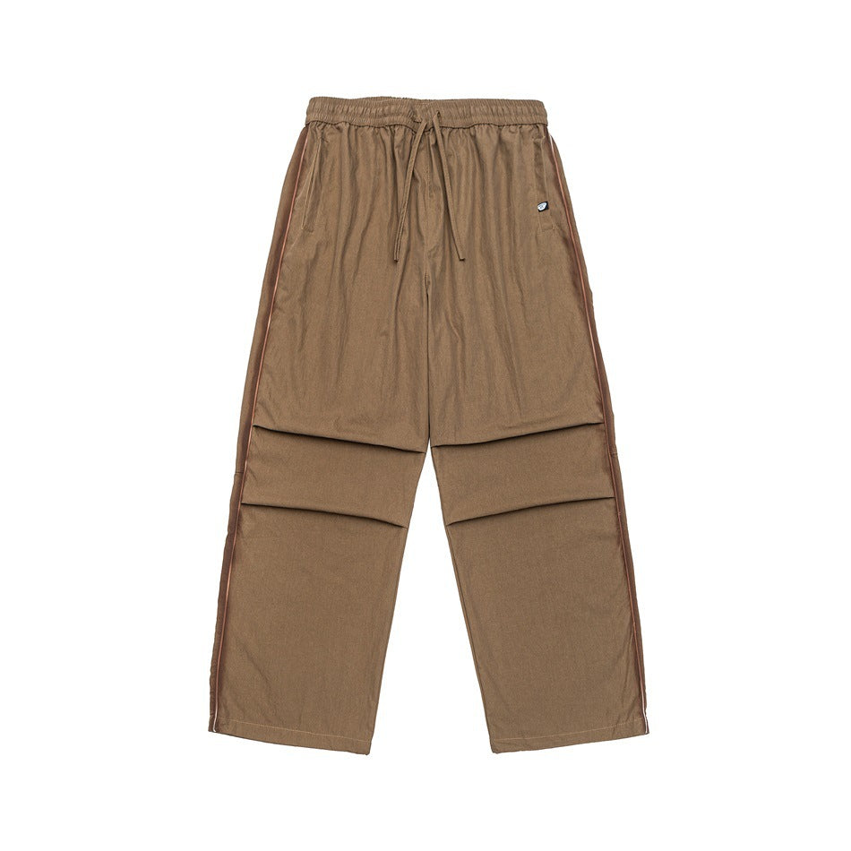 Khaki wide-leg drawstring pants with brown side piping and pleated knees, flat lay front view