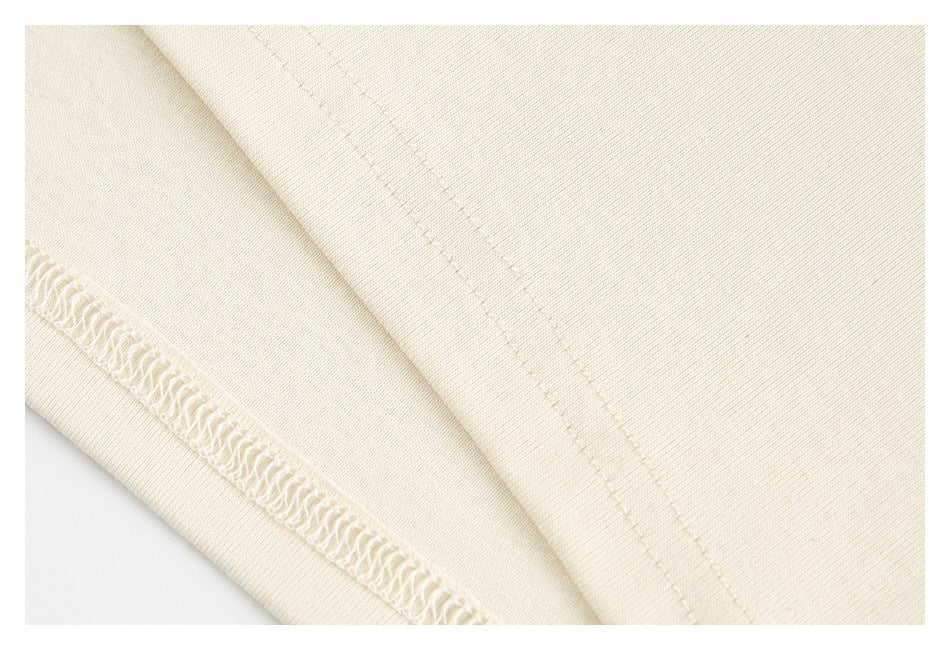 Close-up of cream fabric with a diagonal stitched seam and an exposed overlock edge.