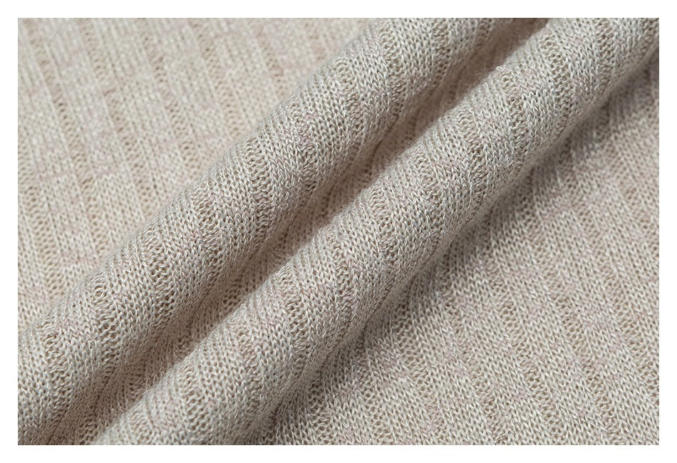 Macro view of beige knit fabric, showing its open stitch texture and softly folded drape.