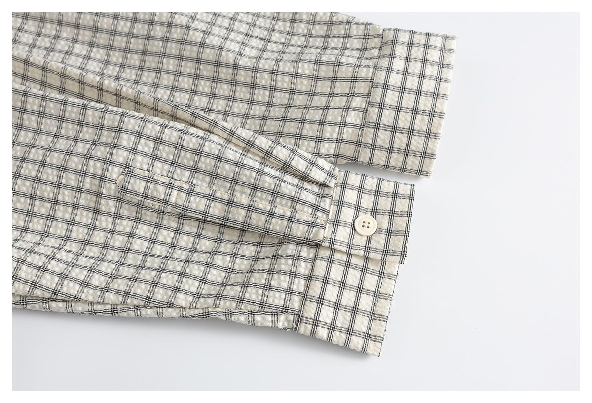 Close-up of an ivory plaid shirt sleeve and buttoned cuff.