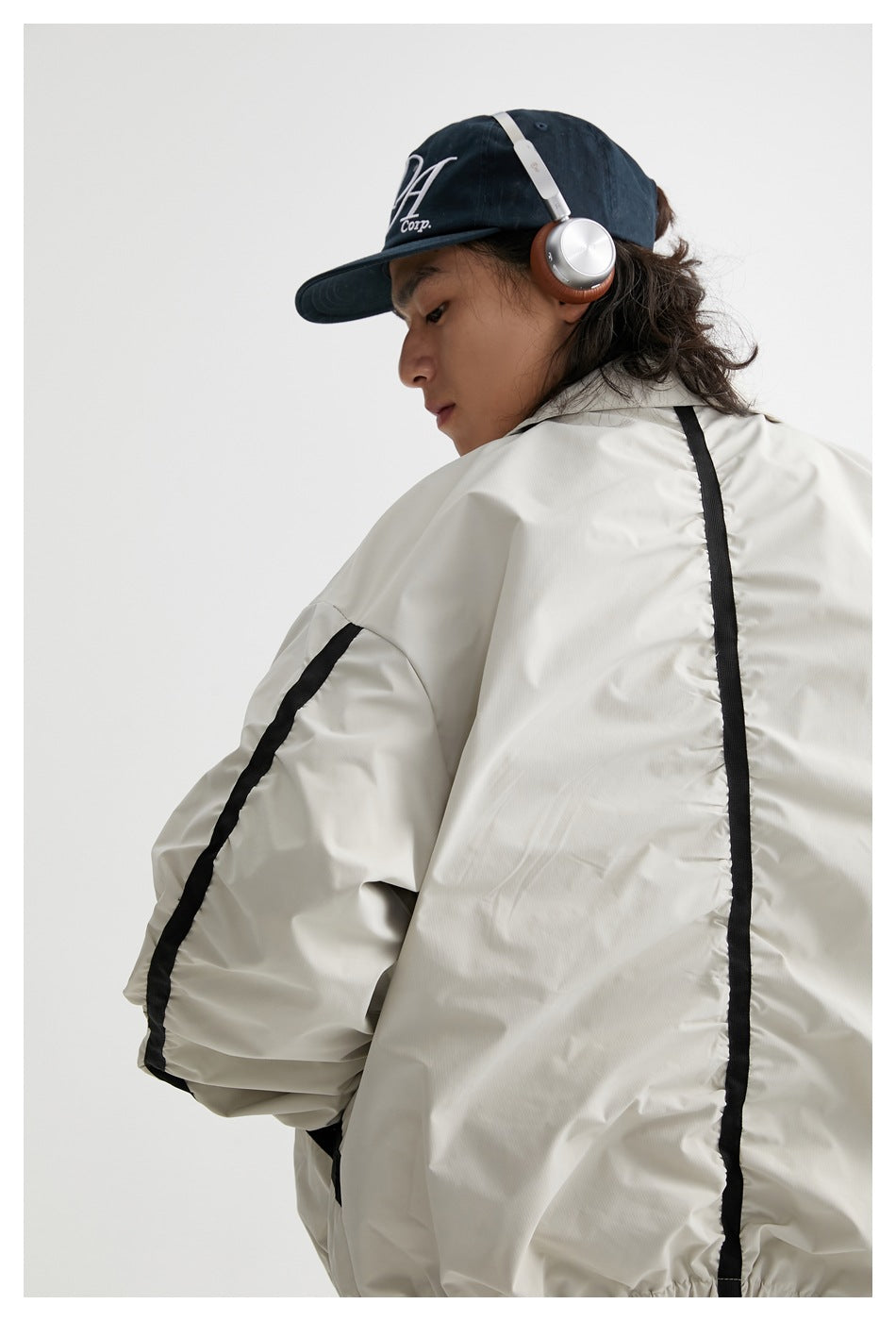 Back view of a model wearing a light gray jacket with a vertical black stripe down the back.