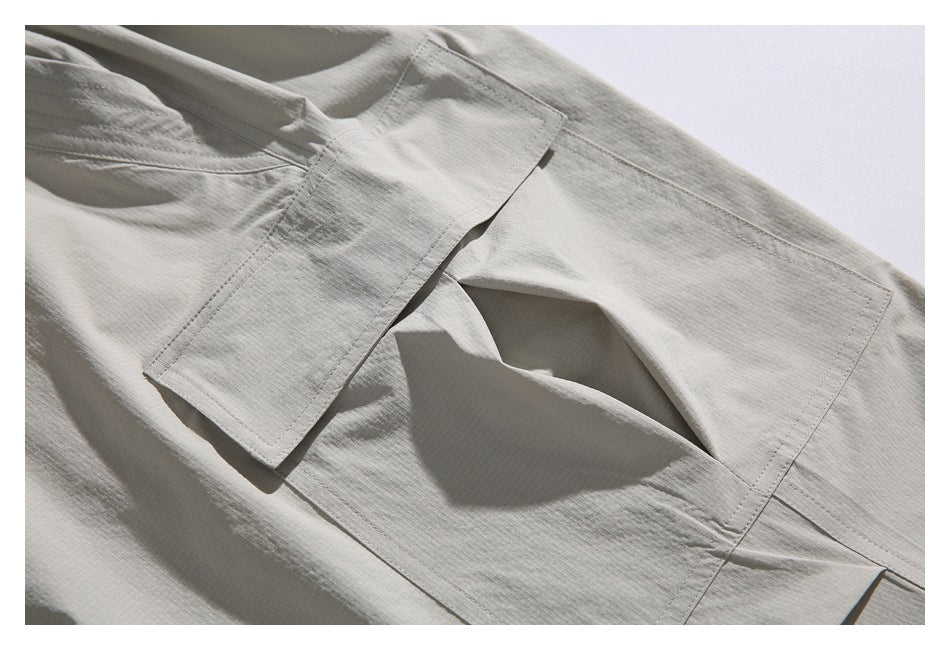 Close-up of a light gray garment with a stitched rectangular pocket flap and matching panel.