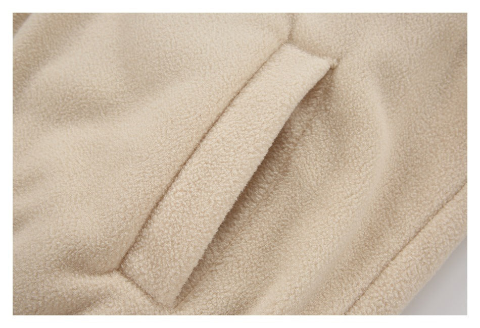Close-up of a cream fleece jacket pocket opening and stitched seams.