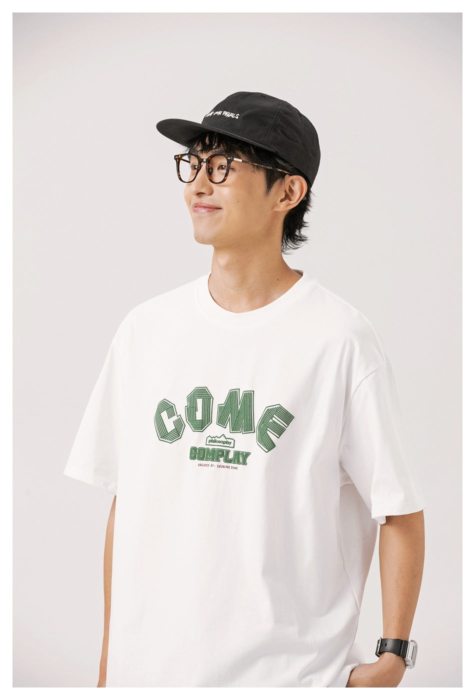 Close view of a model wearing a white T-shirt with a dark-green chest graphic.