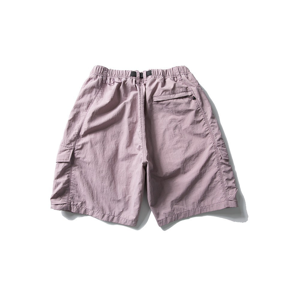 Rear view of pale mauve cargo shorts with an elastic waist, black webbing belt, and side flap pockets.