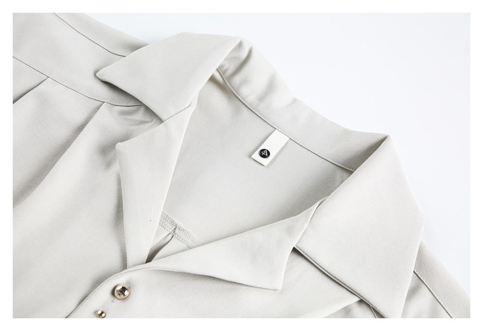 Close-up of the white tunic's wide pointed collar, inner label, and metal front buttons.
