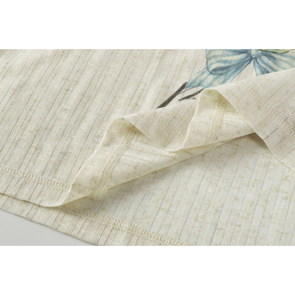 Close-up of the ivory shirt's textured fabric, folded hem and stitched seam.
