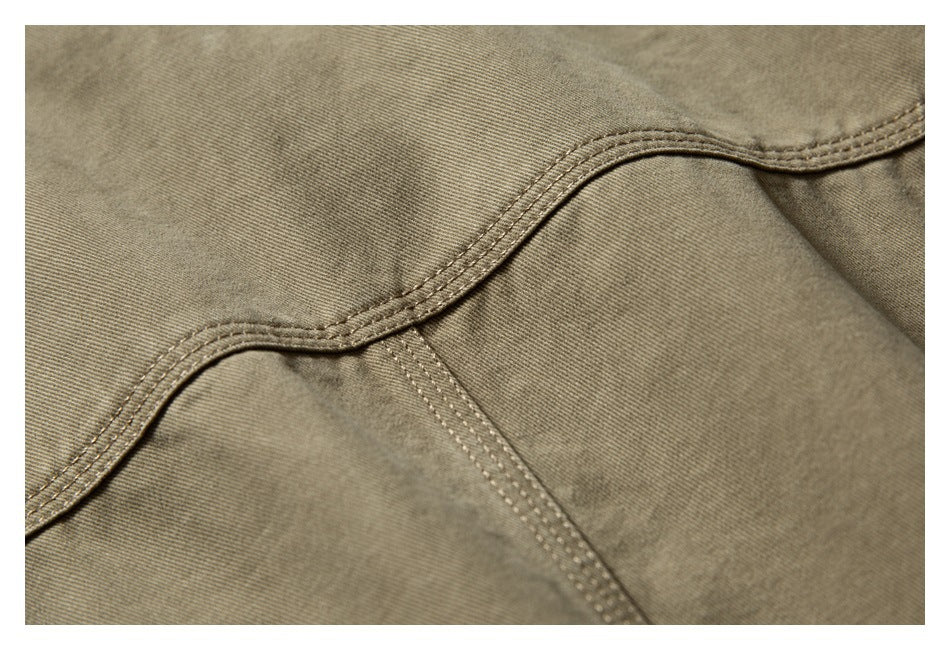 Close-up showing curved double stitching and panel seams on olive-khaki fabric.