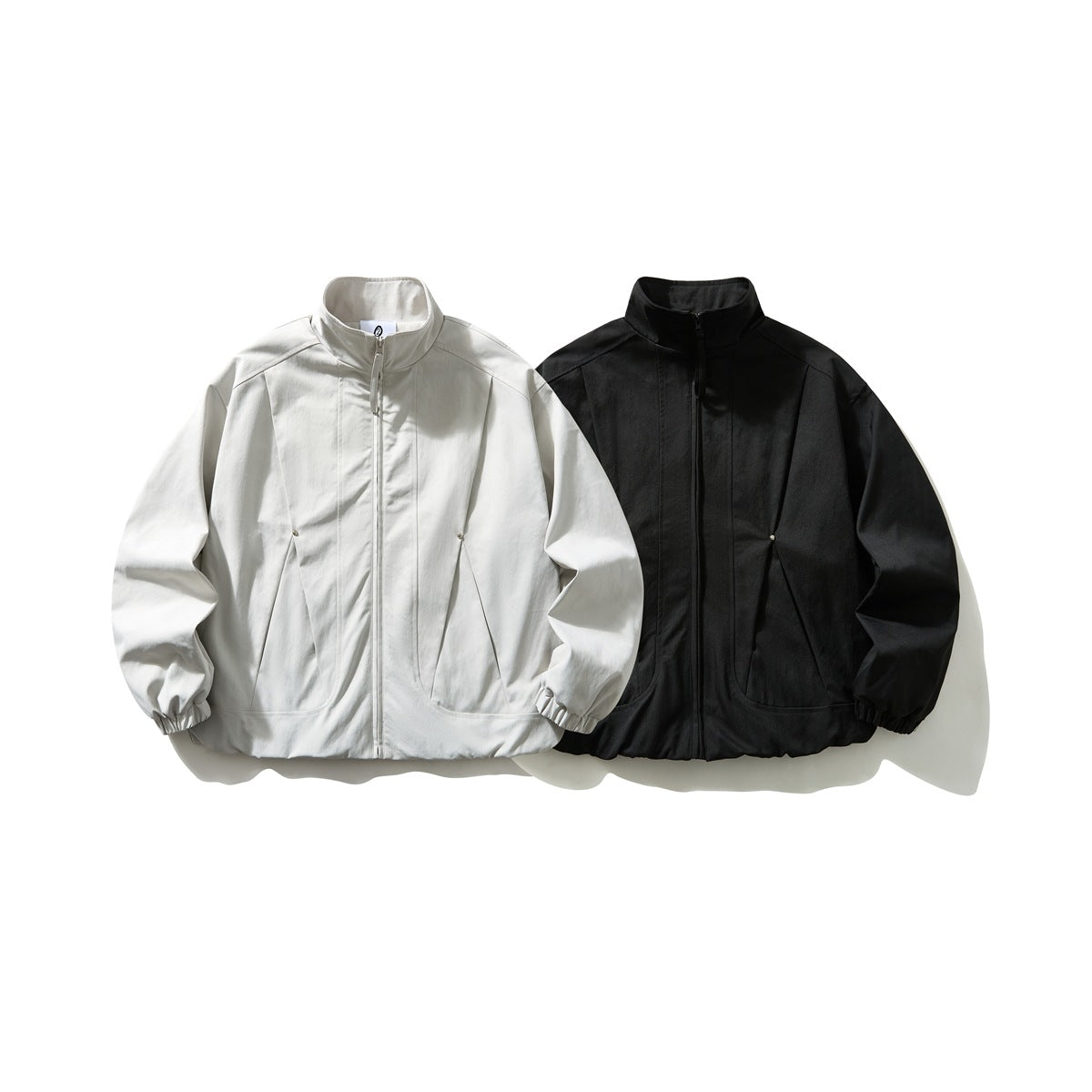 Front view of two stand-collar zip jackets with gathered cuffs, in off-white and black.