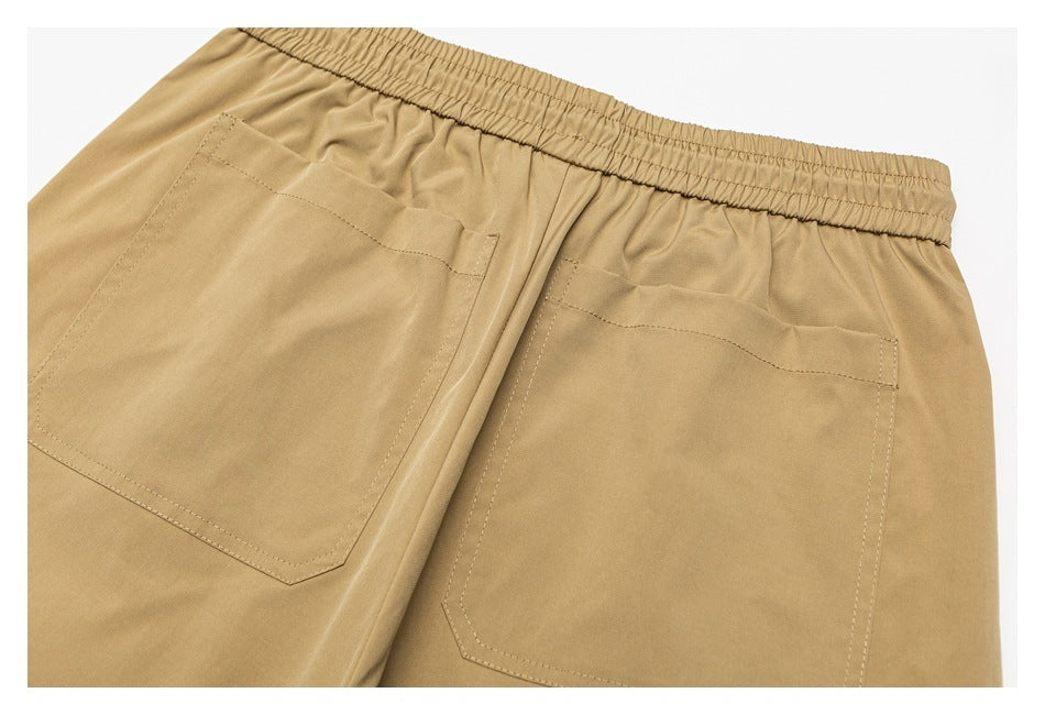 Close-up of the back of tan pants with an elastic waistband and two large patch pockets.