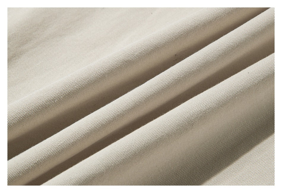 Close-up of beige fabric arranged in soft folds, showing a fine diagonal weave.